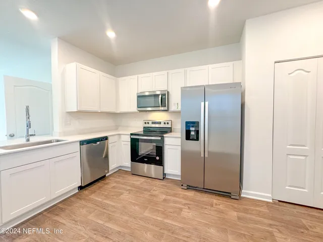 a kitchen with granite countertop a refrigerator and a stove top oven