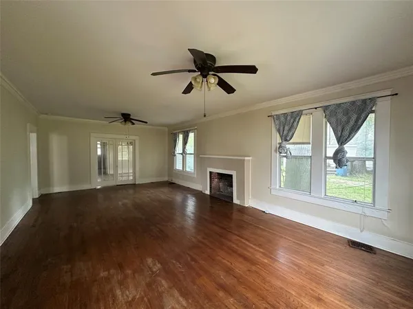 a view of an empty room with wooden floor and a window