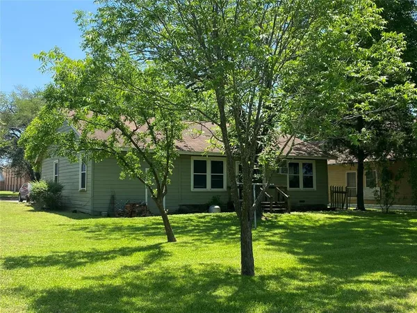 a view of a house with a yard and a large tree
