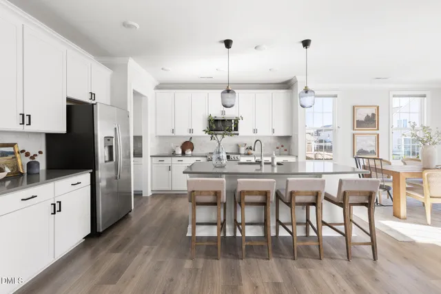 a kitchen with stainless steel appliances a dining table chairs stove and refrigerator
