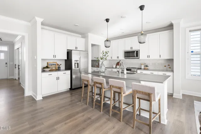 a kitchen with stainless steel appliances kitchen island granite countertop a dining table chairs and white cabinets
