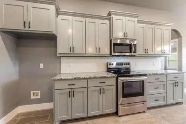 a kitchen with stainless steel appliances granite countertop a stove a sink and a microwave