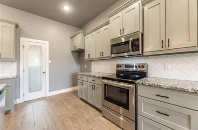 a kitchen with stainless steel appliances granite countertop a stove a microwave and a refrigerator