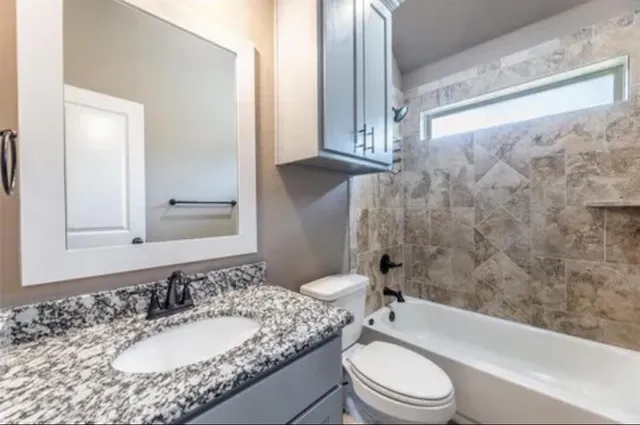 a bathroom with a granite countertop sink toilet a mirror and bathtub