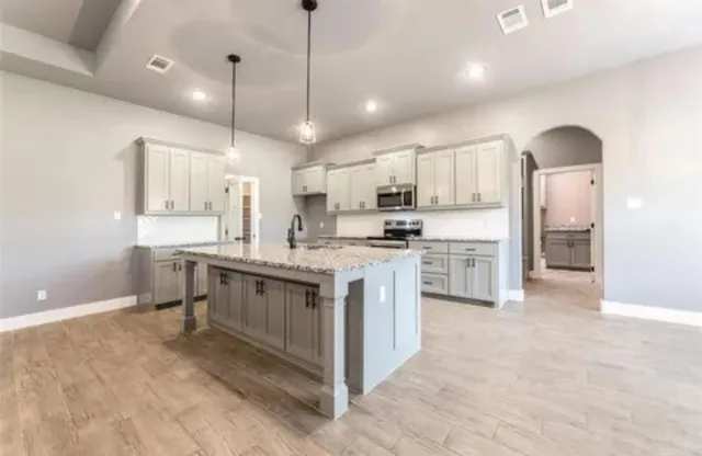 a kitchen with kitchen island granite countertop a stove sink and refrigerator