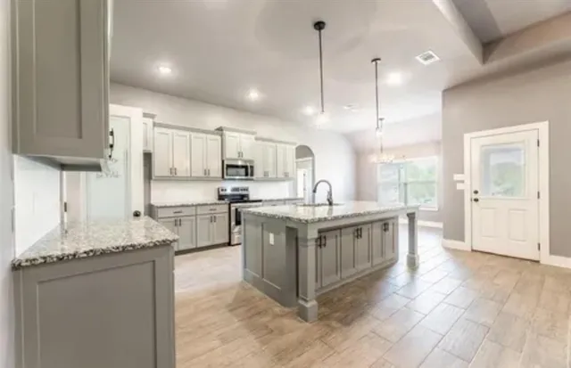 a large kitchen with stainless steel appliances granite countertop a stove a sink and a refrigerator