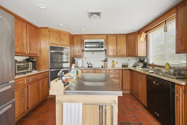 a kitchen with kitchen island granite countertop a sink stove and refrigerator