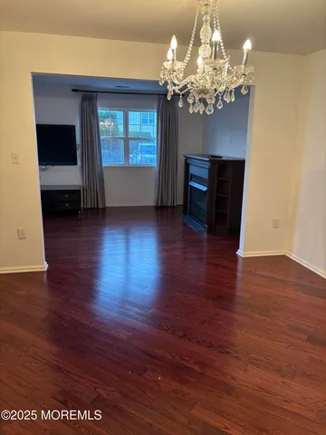a view of a room with wooden floor chandelier and a window