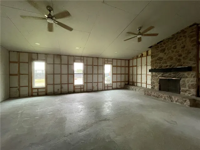 an empty room with windows and fireplace