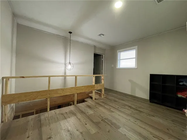 a view of an empty room with wooden floor and windows