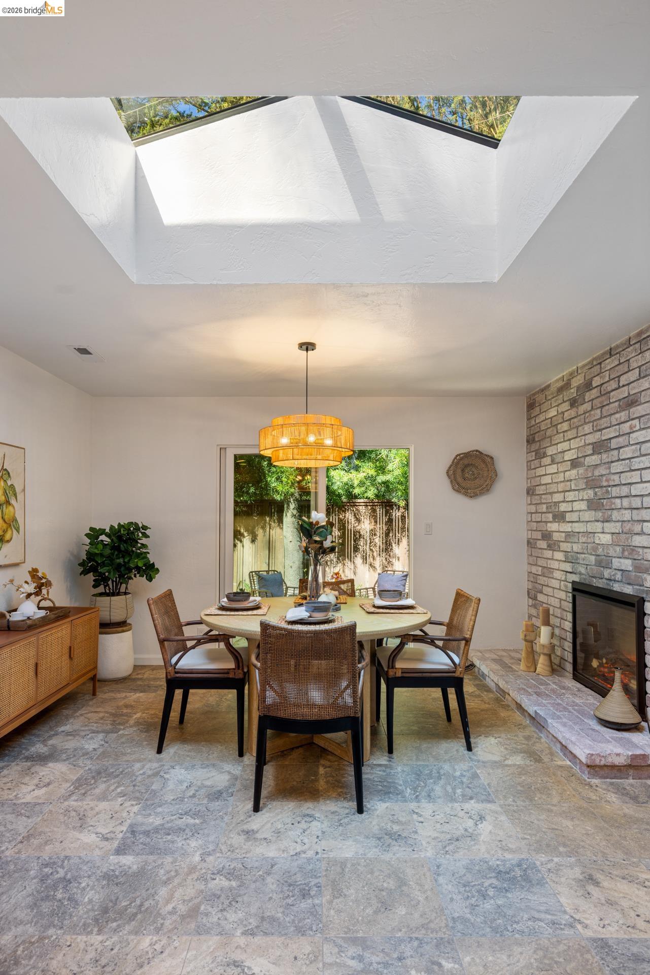 6660 Sobrante Road Oakland, CA 94611 - Photo 9 of 48 Skylight with natural light, brick-faced fireplace, glass sliding door, and stone tile flooring