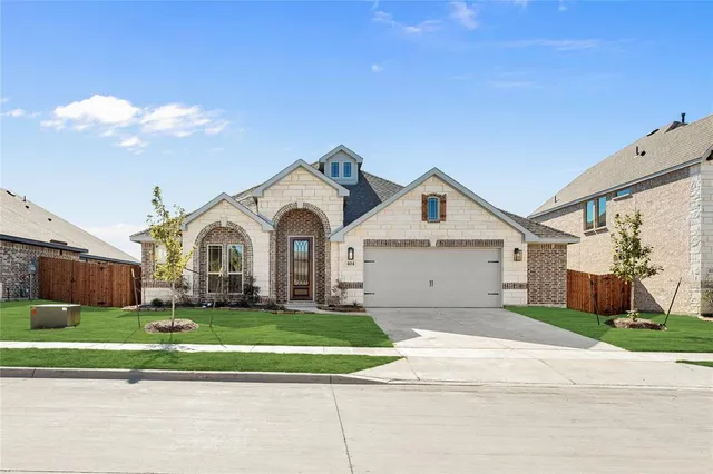 a view of a white house with a big yard and large trees with wooden fence