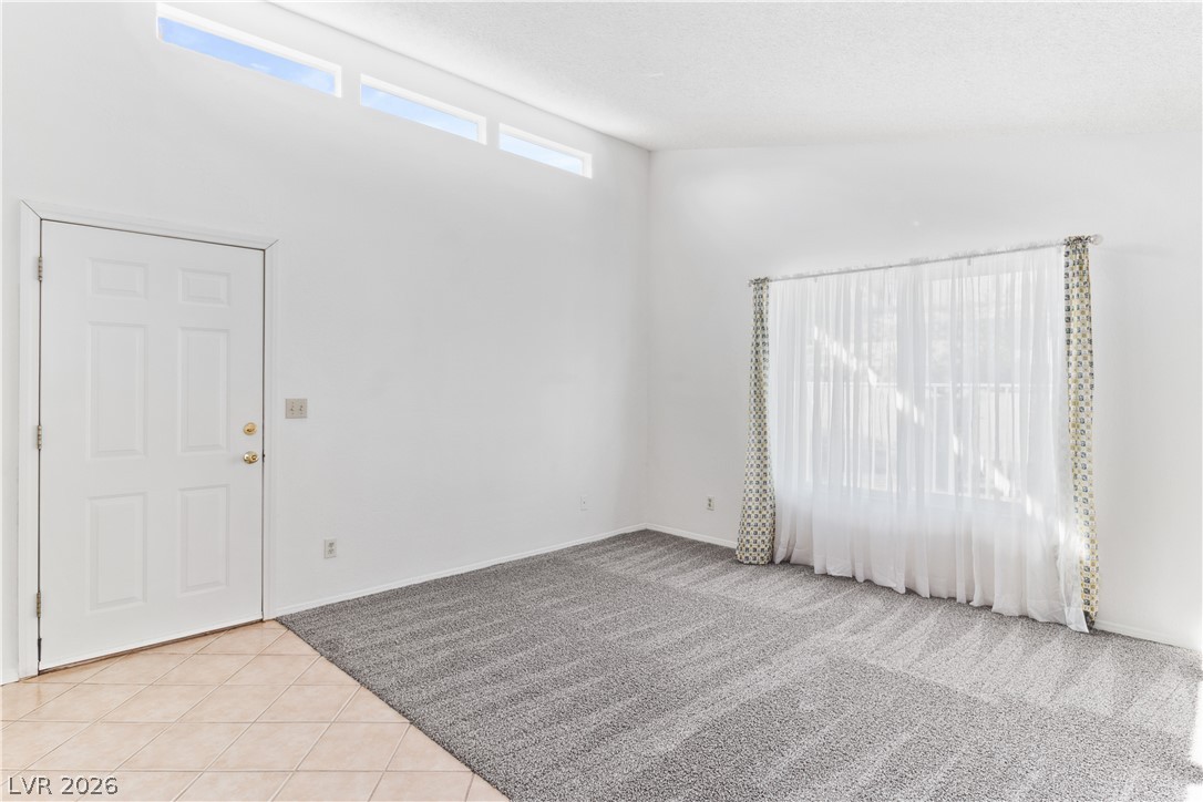 2146 High Dunes Lane Laughlin, NV 89029 - Photo 5 of 64 Family room with light carpet, light tile patterned floors, baseboards, and lofted ceiling