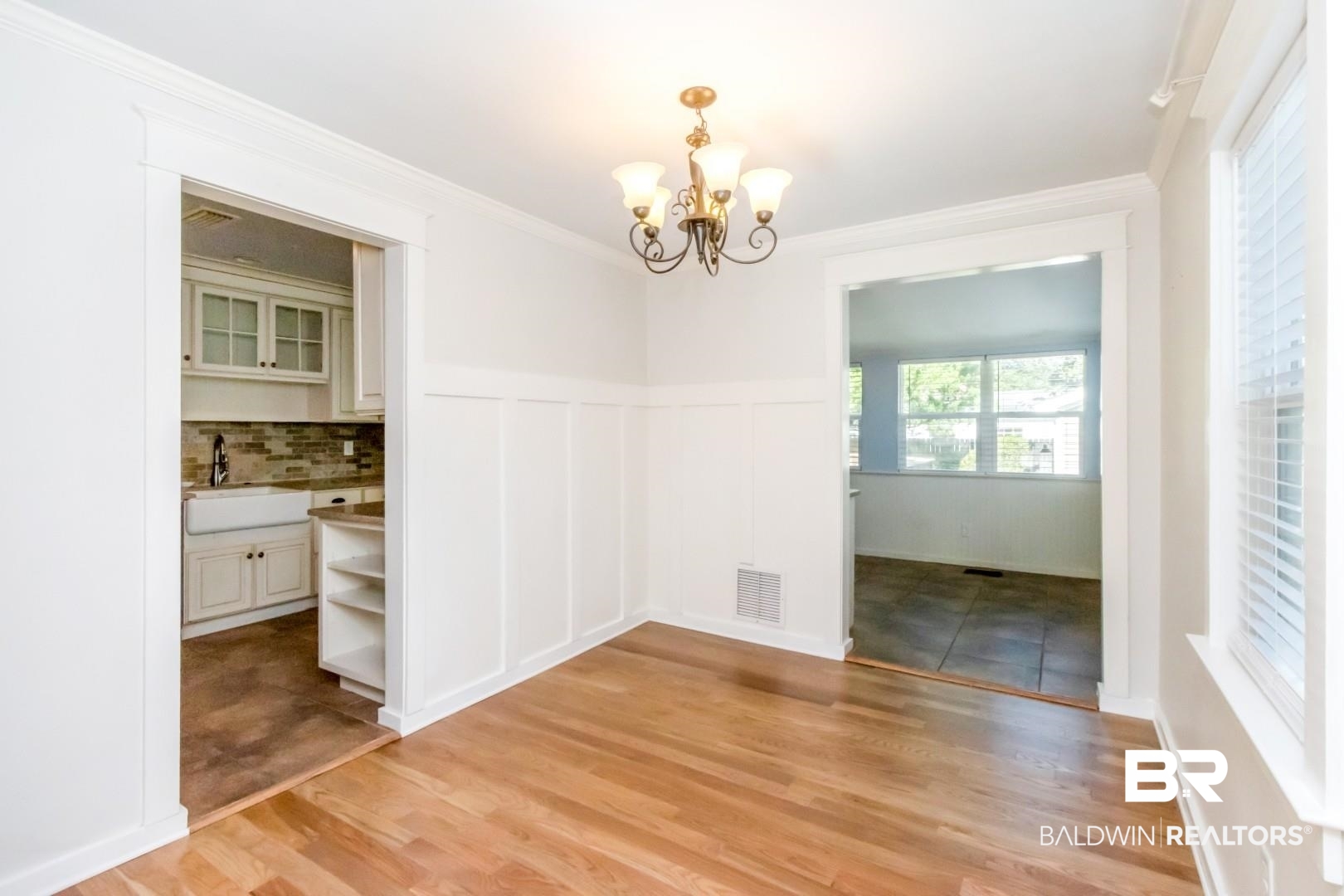 10 South Hathaway Road Mobile, AL 36608 - Photo 14 of 46 Unfurnished dining area with wainscoting, a chandelier, light wood-type flooring, crown molding, and a decorative wall
