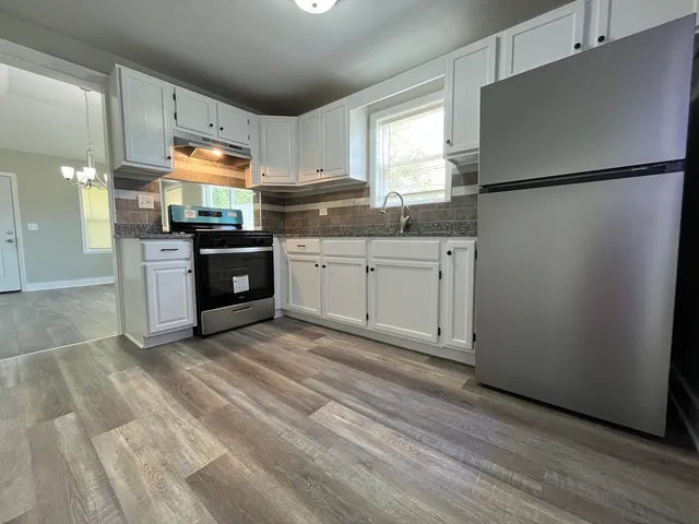 a kitchen with stainless steel appliances granite countertop a refrigerator sink and stove