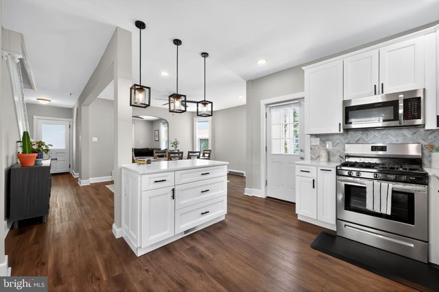 a kitchen with stainless steel appliances white cabinets a stove a sink and a wooden floors