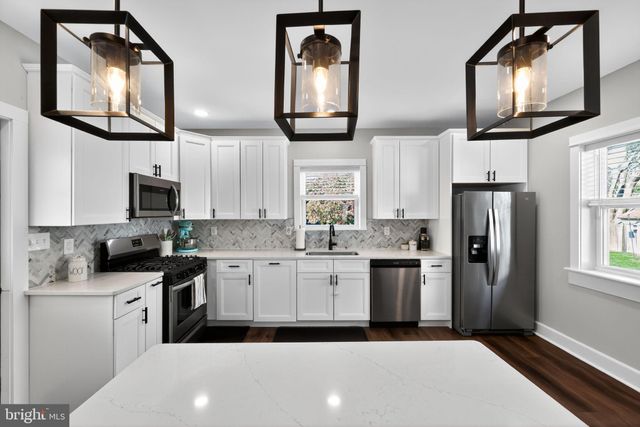 a kitchen with stainless steel appliances granite countertop a refrigerator a stove top oven a sink and dishwasher next to a window