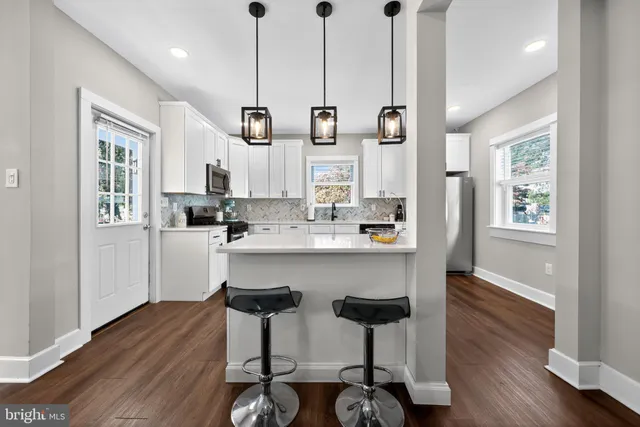 a kitchen with stainless steel appliances kitchen island wooden floors and white cabinets