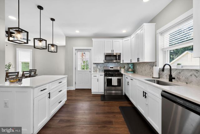 a kitchen with stainless steel appliances kitchen island granite countertop a sink and dishwasher a stove top oven with wooden floor