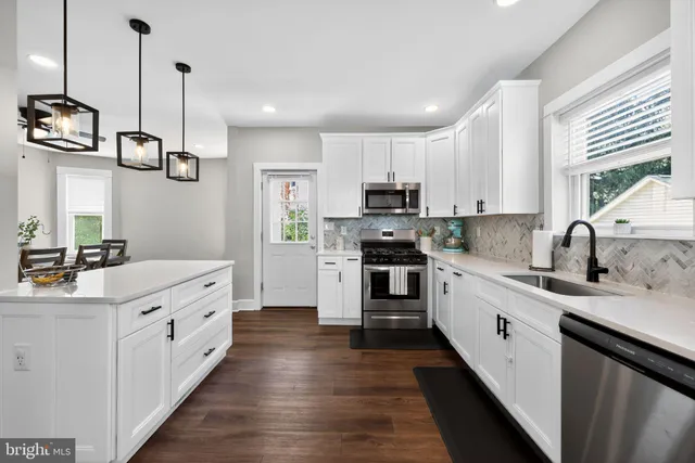 a kitchen with stainless steel appliances kitchen island granite countertop a sink and dishwasher a stove top oven with wooden floor