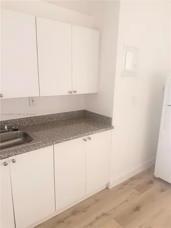 a kitchen with granite countertop white cabinets and a sink