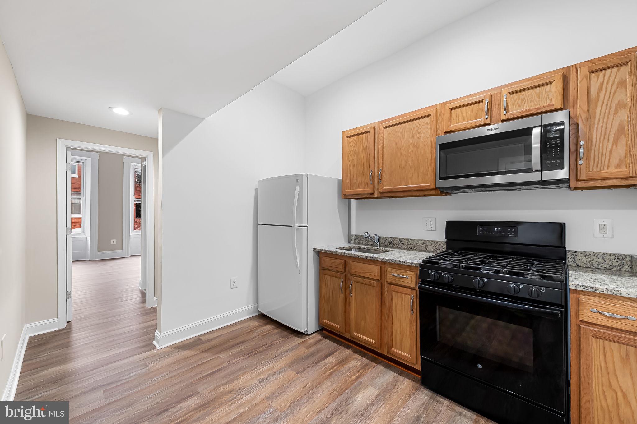 1005 Edmondson Avenue Baltimore, MD 21223 - Photo 19 of 45 a kitchen with stainless steel appliances granite countertop a stove microwave and refrigerator