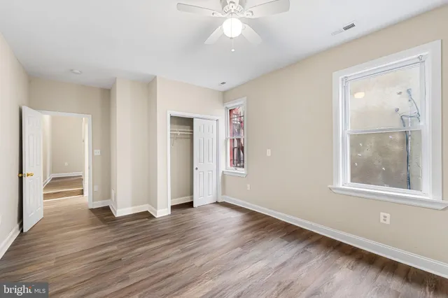an empty room with wooden floor and windows