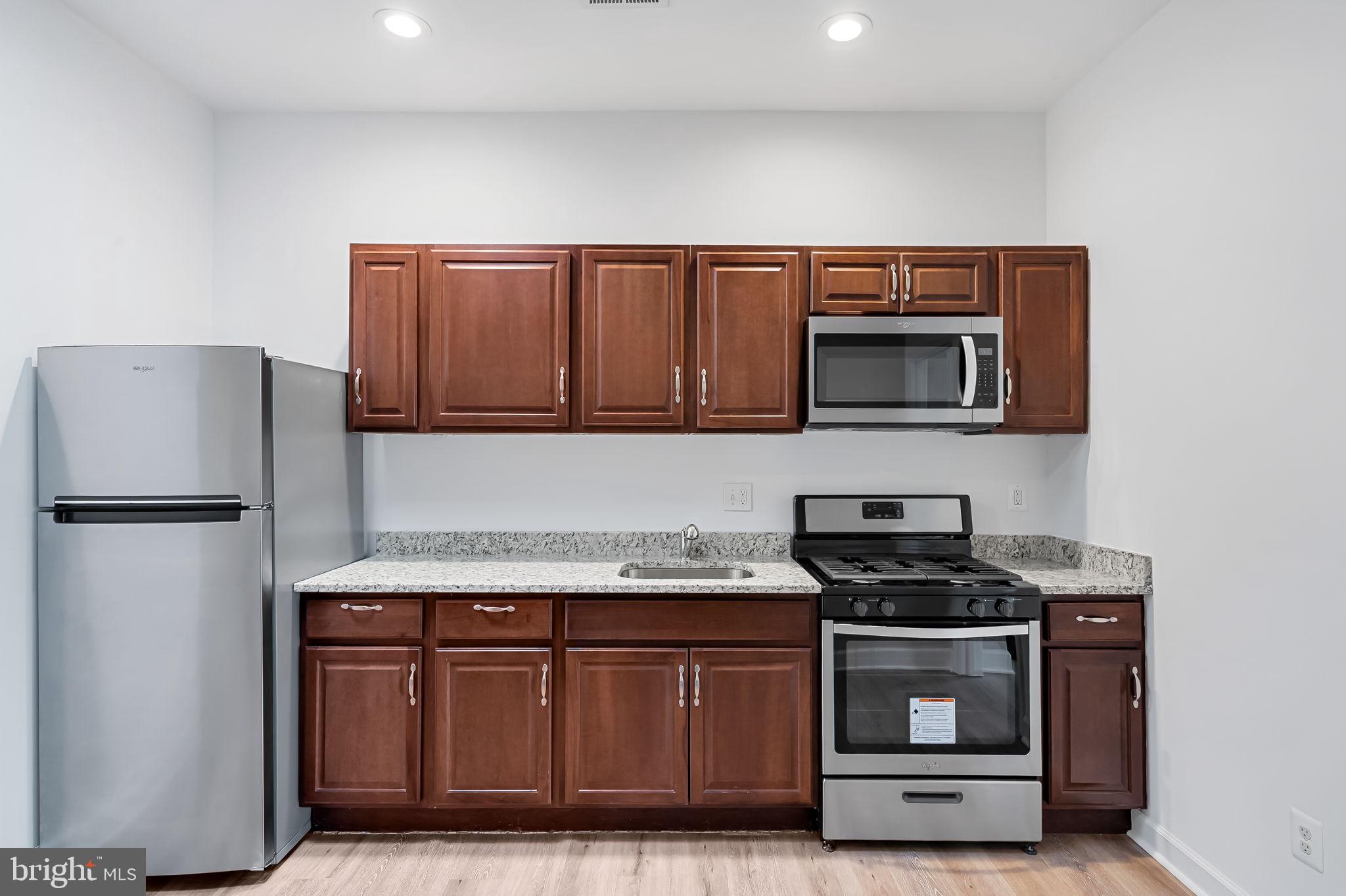 1005 Edmondson Avenue Baltimore, MD 21223 - Photo 33 of 45 a kitchen with stainless steel appliances wooden cabinets and a refrigerator