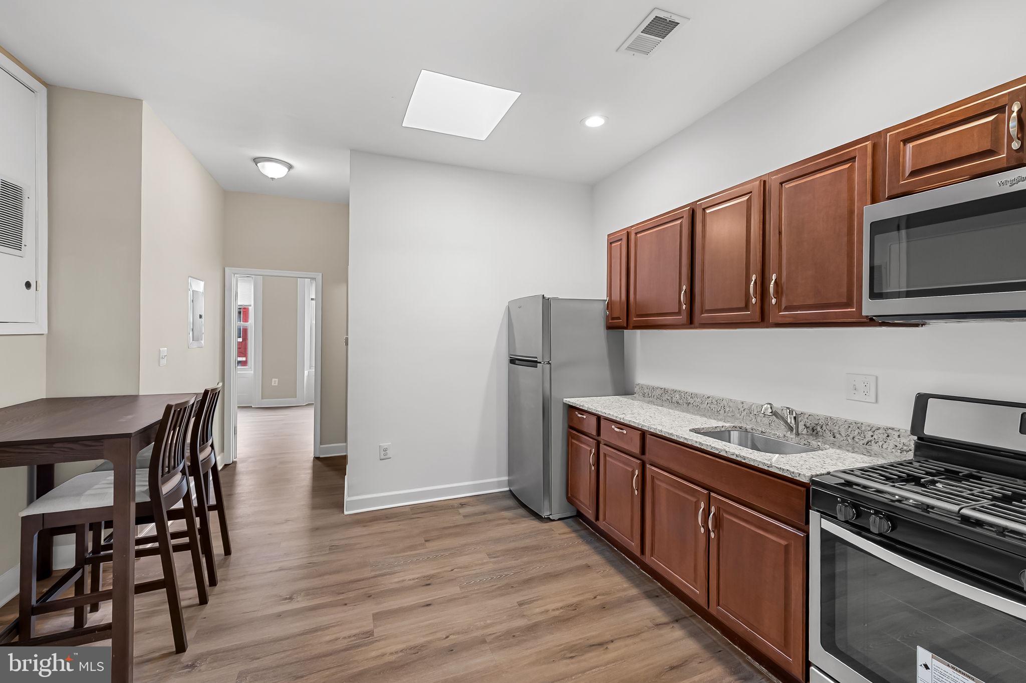 1005 Edmondson Avenue Baltimore, MD 21223 - Photo 35 of 45 a kitchen with stainless steel appliances granite countertop a stove a sink dishwasher a refrigerator with wooden cabinets and floor