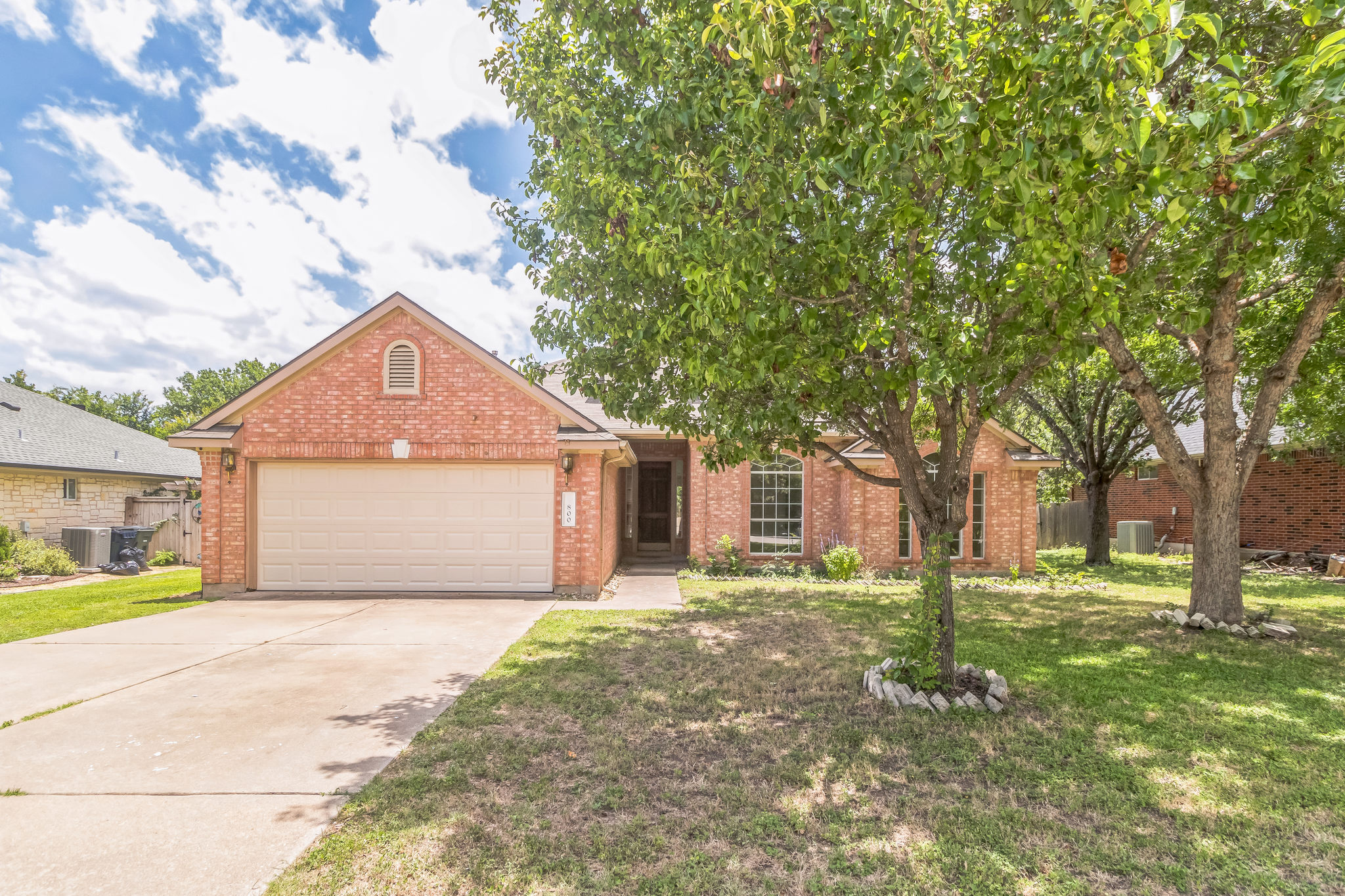 800 Mountain Ridge Drive Leander, TX 78641 - Photo 1 of 31 Mature trees frame the classic brick facade and concrete driveway of this welcoming home.