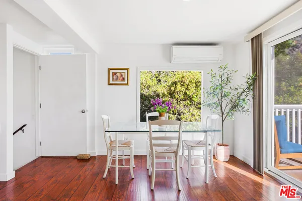 a view of a dining room with furniture a potted plant and wooden floor