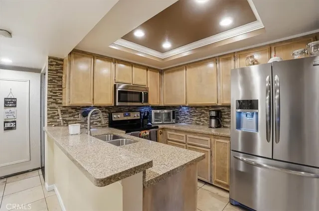 a kitchen with stainless steel appliances kitchen island granite countertop a refrigerator a stove a sink a dining table and chairs with wooden floor
