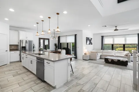a large white kitchen with a large window and stainless steel appliances