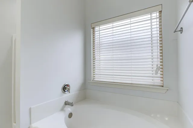 an empty room with a window and a chandelier fan