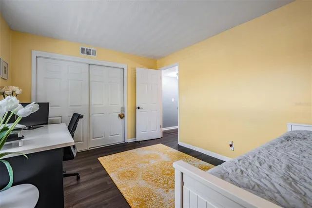 a bedroom with a bed and a chair with the wooden floor