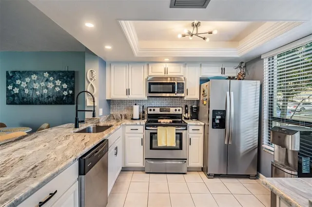 a kitchen with kitchen island granite countertop a refrigerator stove microwave and sink