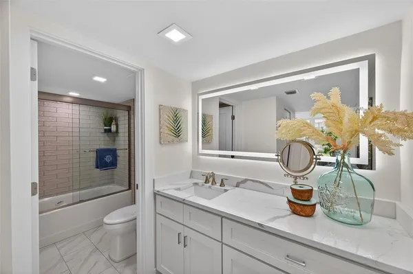 a bathroom with a granite countertop sink a toilet and shower