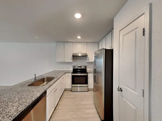 a kitchen with stainless steel appliances granite countertop a refrigerator and a sink