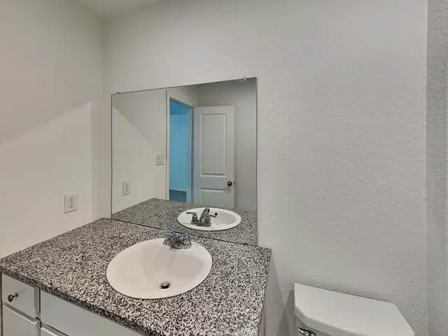 a bathroom with a granite countertop sink a toilet and a mirror