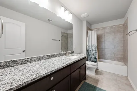 a bathroom with a granite countertop sink and a bathtub
