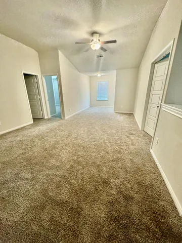 an empty room with chandelier fan and windows