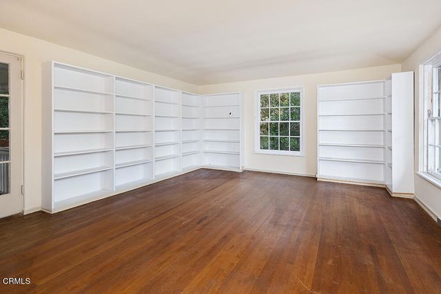 a view of an empty room with wooden floor and windows