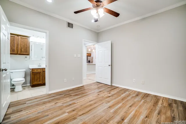 a view of empty room with wooden floor and fan