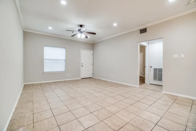an empty room with windows and ceiling fan