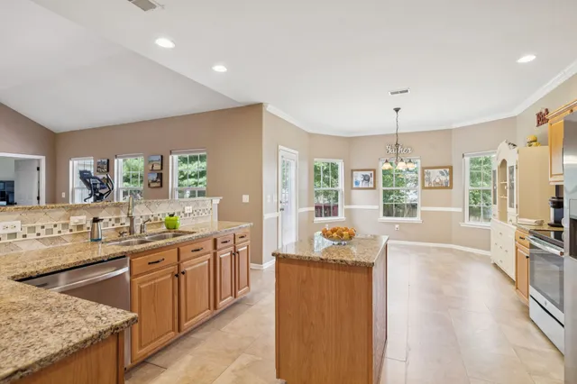a large kitchen with kitchen island a large counter top space a sink stainless steel appliances and cabinets
