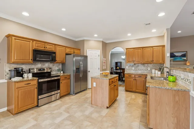a kitchen with stainless steel appliances granite countertop sink stove top oven and refrigerator