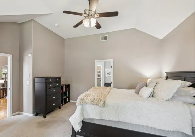 a bedroom with a bed a dresser and a chandelier