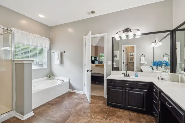 a spacious bathroom with a tub sink shower and mirror