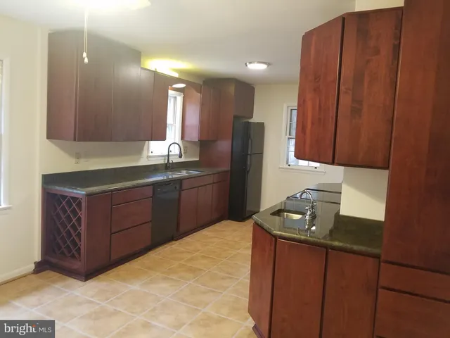 a kitchen with stainless steel appliances granite countertop a refrigerator a sink and wooden cabinets