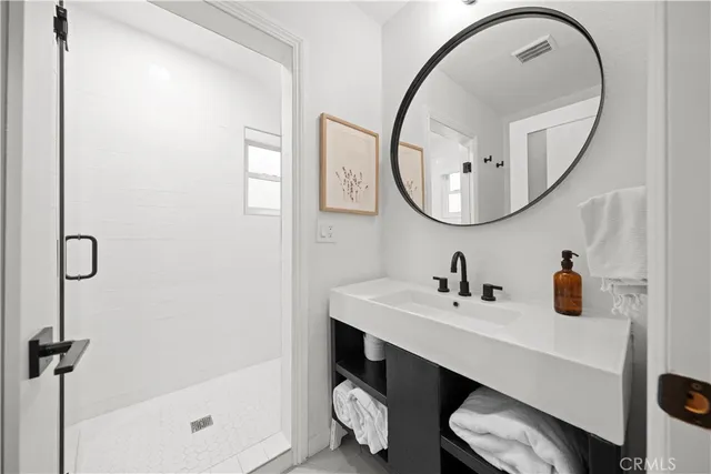 a bathroom with a sink a mirror a vanity and a shower